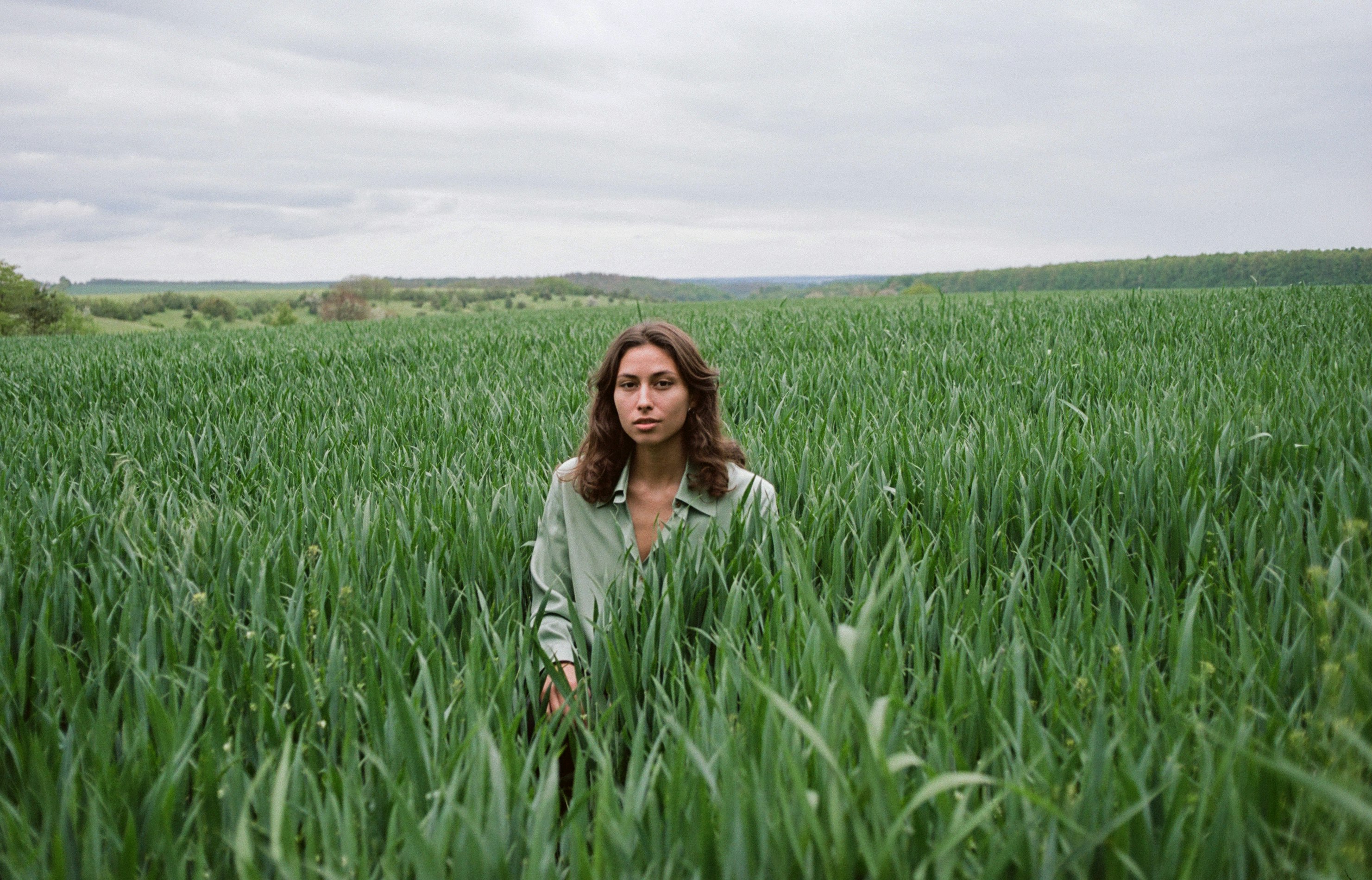 woman in gray jacket standing on green grass field during daytime